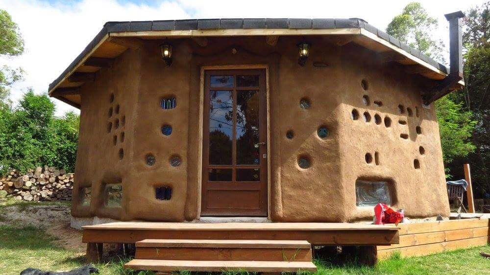 Cabaña de adobe terminada con detalles de botellas de colores