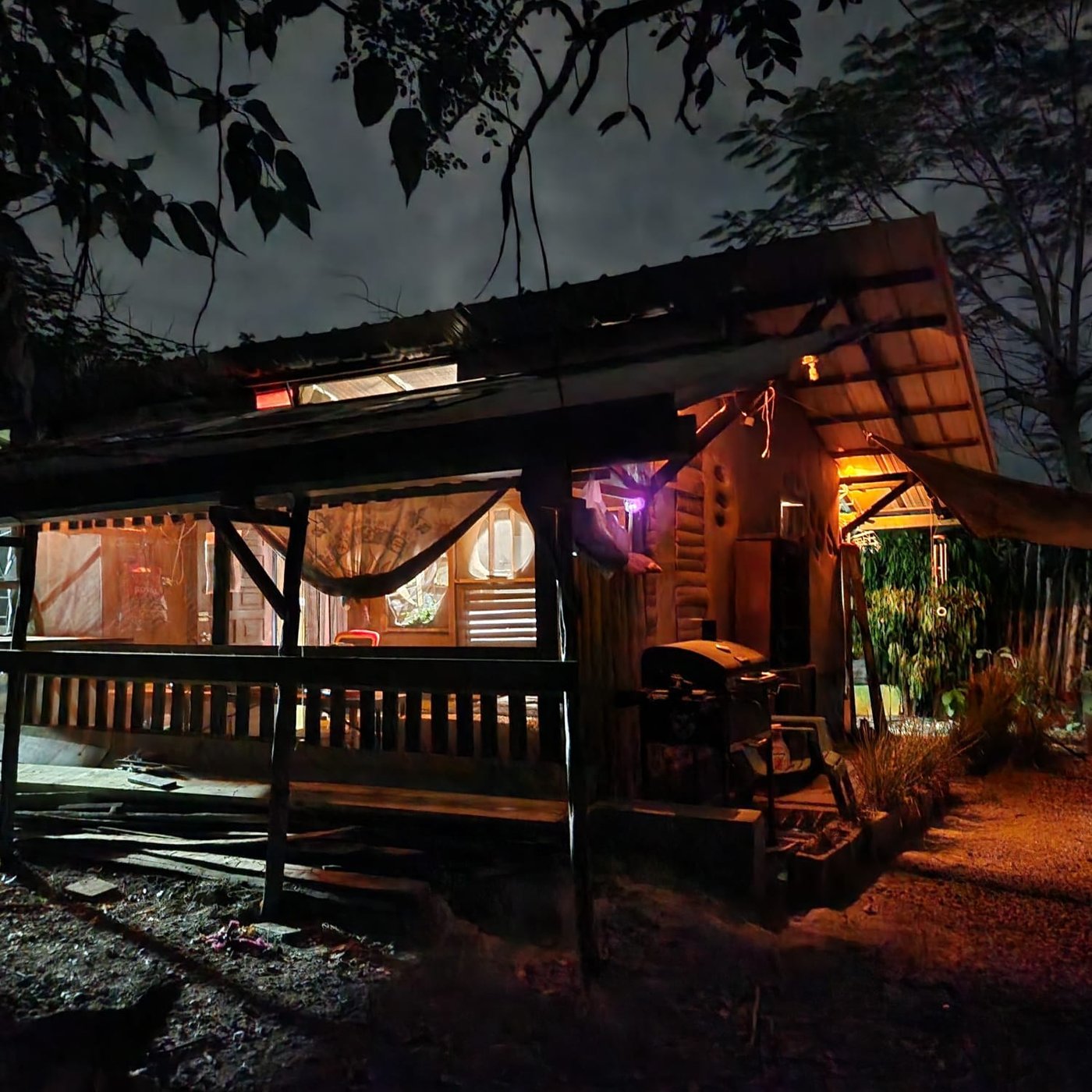 Rancho Coa de noche, con el porche iluminado, el techo de chagüí y el jardín alrededor